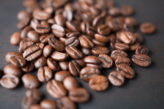 Freshly roasted whole coffee beans scattered on a dark surface