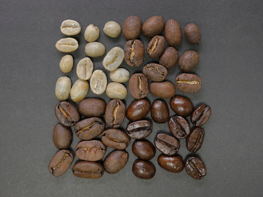 Whole roasted coffee beans scattered on a surface showing different shades of brown roast levels
