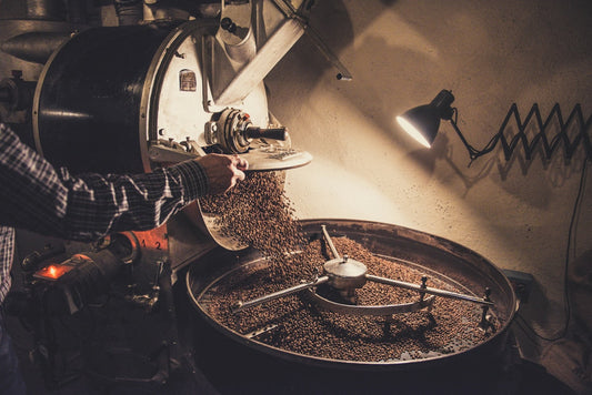 Coffee roaster releasing freshly roasted beans into a cooling tray at a small batch roastery