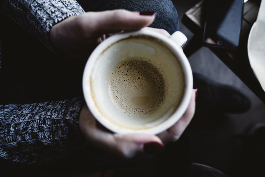 Person holding a warm latte in a white ceramic mug, enjoying specialty coffee