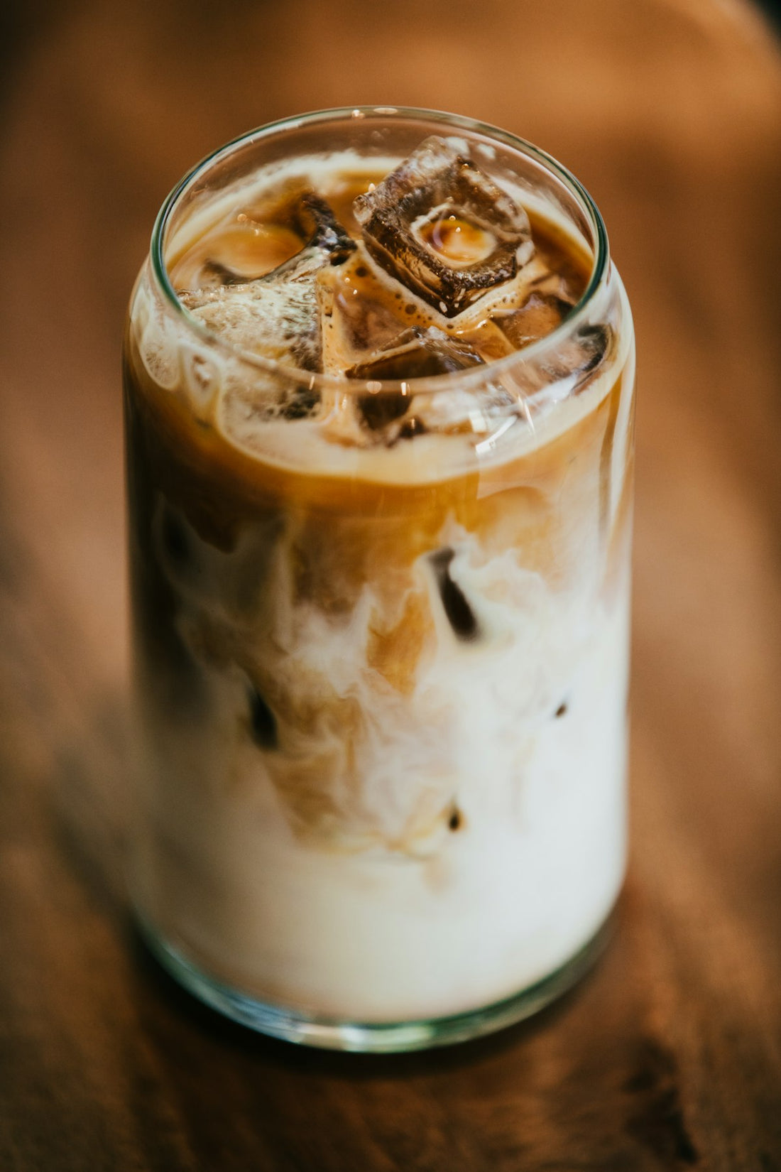 An iced latte in a glass with espresso swirling into cold milk over ice