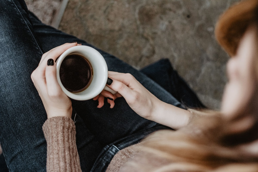 Hands holding a warm mug of coffee viewed from above in a cozy morning setting