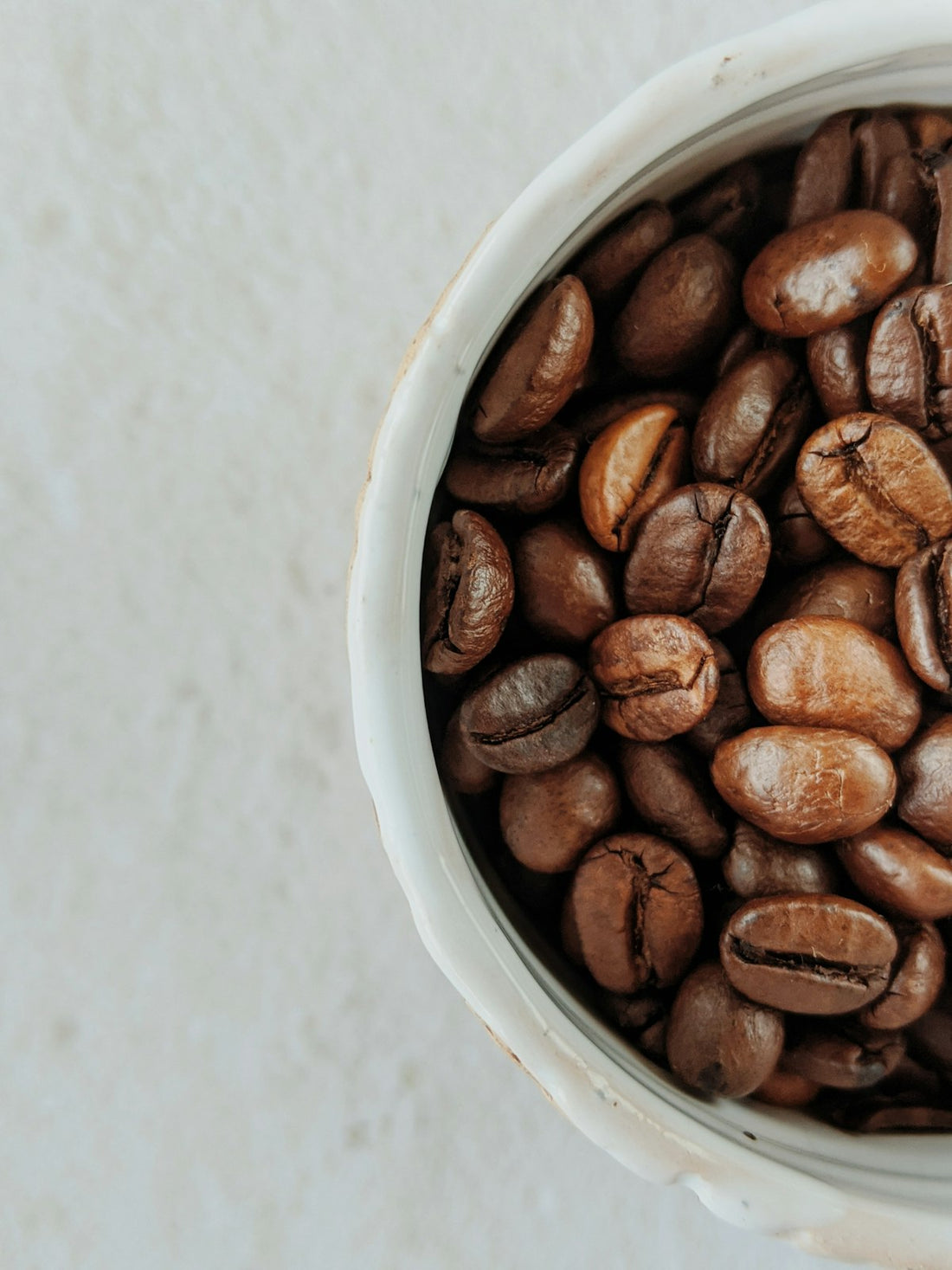Close-up of roasted coffee beans in a white ceramic bowl