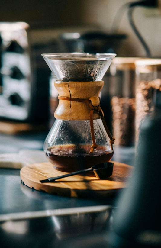 Chemex coffee brewer with freshly brewed coffee on a wooden board