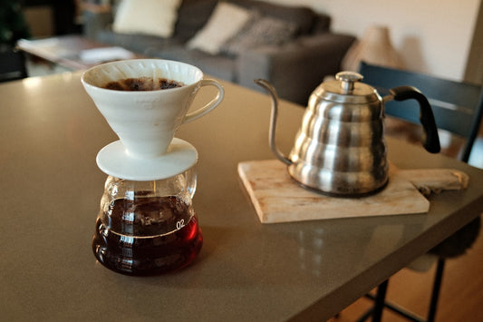 Pour-over coffee maker and gooseneck kettle on a table, ready for brewing